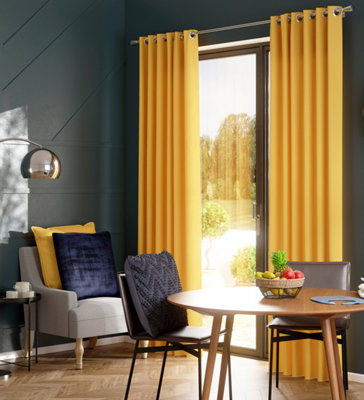 A navy blue and yellow living room with light wooden flooring, geometric wall panels, and bright yellow curtains.