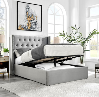 Olivia Grey Velvet Double 4FT 6 Fabric Wingback Ottoman Storage Gas Lift Bed Frame With Antique Stud Detail