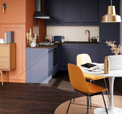Orange walls, dark blue kitchen cabinets, and dark wooden worktops and flooring.
