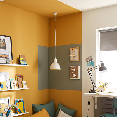 A child's reading nook painted in a bright yellow and grey, contrasting to the rest of the white bedroom. Shop GoodHome emulsion paint.