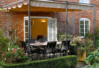 A garden dining area sheltered by a retractable pergola canopy.