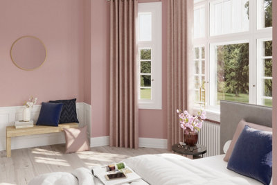 Blush pink bedroom with white wall panelling on lower half of wall and light wood effect laminate flooring.