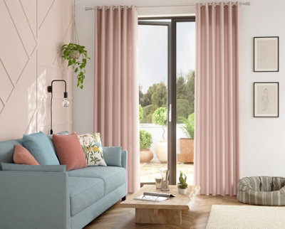 A pale pink living room with blue sofa and a rustic wooden coffee table.