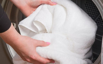 Person loading a towel into a washing machine.