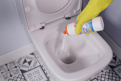 Person wearing rubber gloves pouring baking soda into a toilet bowl.