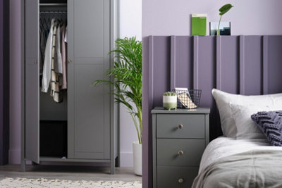 Purple wall panelled headboard behind a bed.
