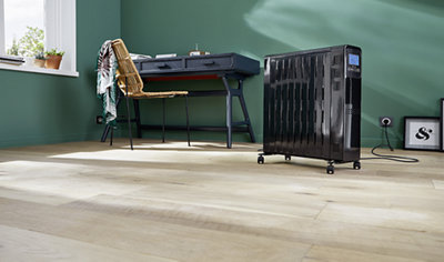 Freestanding black electric radiator with wheels connected to mains socket.