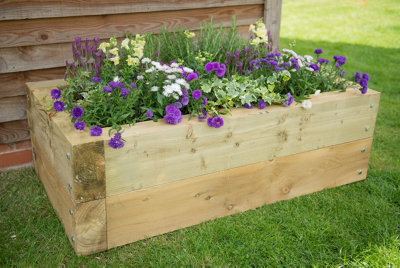 A completed small rectangular wood planter with a variety of colourful flowers planted in the middle.
