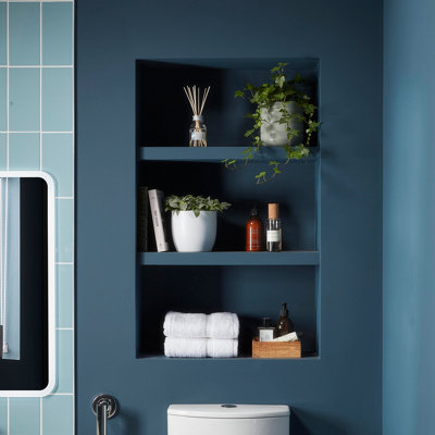 Recessed shelf with plants, towels and fragrance in blue bathroom above the toilet.