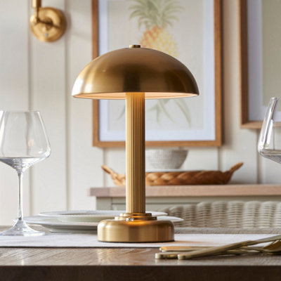 Rechargeable gold, mid-century table lamp placed on dining table.