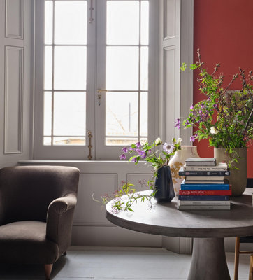 A red and white living room with a grey circular table and brown armchair.