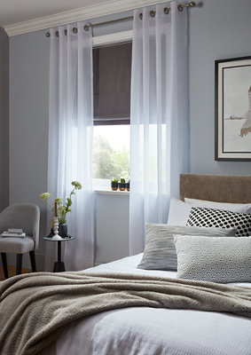 Roller blinds and curtains in a bedroom.