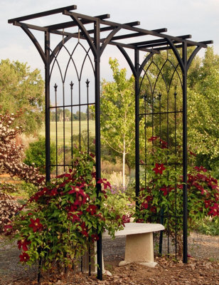 Charming black metal arbour adorned with climbing vines like clematis and jasmine.