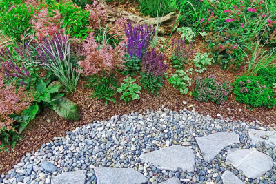 Rustic stepping stones placed over smooth grey pebbles, creating a charming garden pathway.