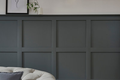 Square grid shaker style wall panelling in dark grey finish below white wall.