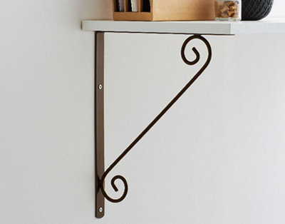 A decorative metal shelf bracket with a straight piece of metal on the wall, a straight piece underneath the shelf, and a decorative metal piece with a spiral at both ends connecting them.
