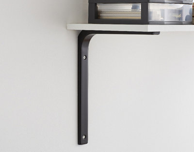 A black regular-load shelf bracket supporting a shelf with office supplies neatly arranged on top.