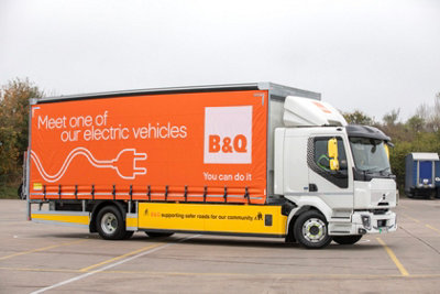 Side view of an orange B&Q electric van in a car park.