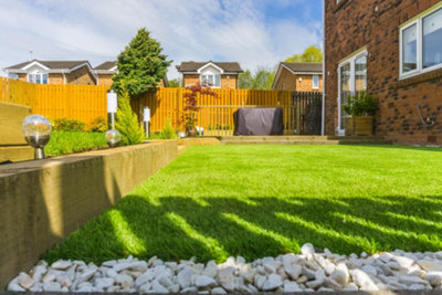 Modern garden with a minimalist design, featuring a well-maintained lawn, raised beds, and sleek white pebbles for a contemporary, low-maintenance space.