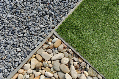 Close-up of a garden ground design with grey gravel, light brown pebbles, and grass, separated by a thin wooden border.