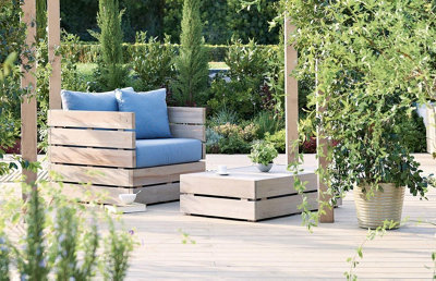 Garden with a cohesive design, featuring a wooden armchair and coffee table made from the same wood as the decking.