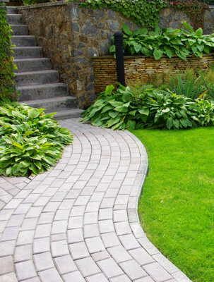 A curved grey brick pathway weaving through a garden lawn.