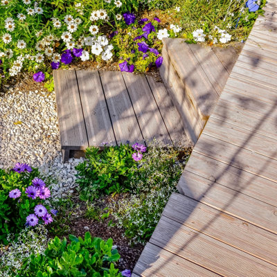 A close up of a small raised deck in a garden, including the steps leading up to the deck.