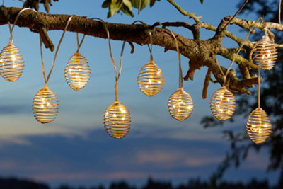 Solar powered garden lights hung from the branch of a tree in a garden.
