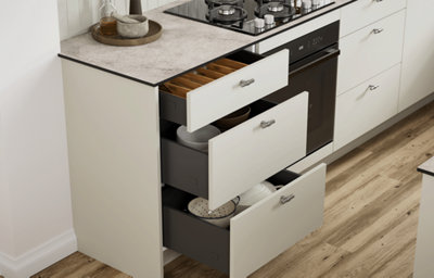 Open kitchen drawers showing organised storage beneath a light stone-effect worktop.