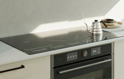 Close up of a large flush induction hob on a bright white worktop.