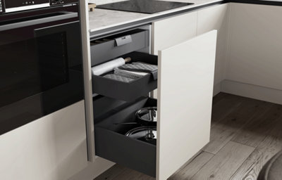 Open kitchen drawers with organised storage beneath a marble-effect worktop.
