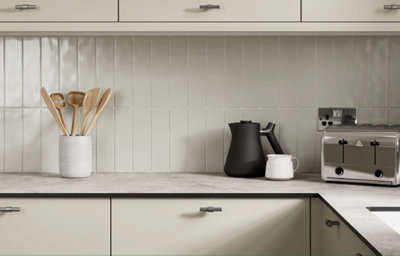 Light stone-effect worktop with pale vertical tiles and simple kitchen accessories.