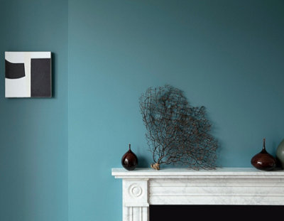 A teal blue living room with a marble mantelpiece and ornaments.