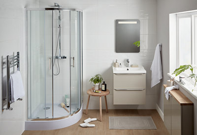 A white bathroom with stand alone shower cubicle, sink, a small wooden stool and light brown wooden flooring.