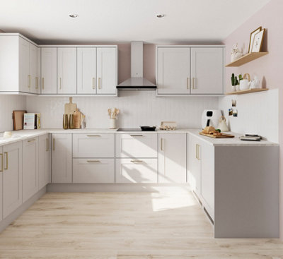 Tidy kitchen with light cream cabinets, white splashback, pale pink walls, and metallic accents.