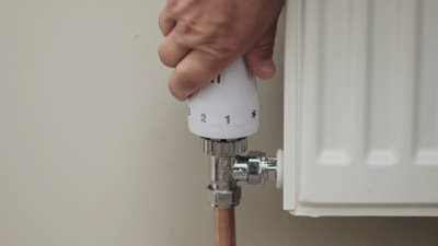 Close up of a hand turning a TRV valve to zero.