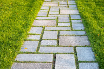 A garden path with paving slabs of different sizes arranged in a mix of horizontal and vertical positions across a green lawn.