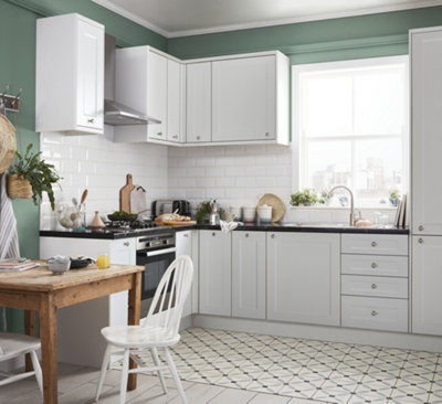 A white and green kitchen with a fold down wooden table against one wall.