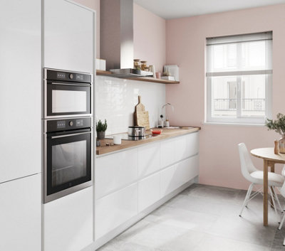 White and pink kitchen with white cabinetry, wooden worktops, and light pink painted walls.