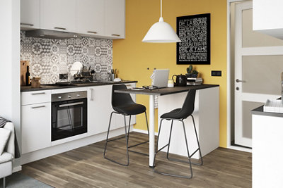 A small kitchen with white cabinets, a yellow feature wall, and a small kitchen island with a black worktop.