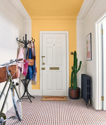 A hallway with a bold painted strip of yellow on the wall and ceiling, visually elongating the space and creating a brighter, more open feel.