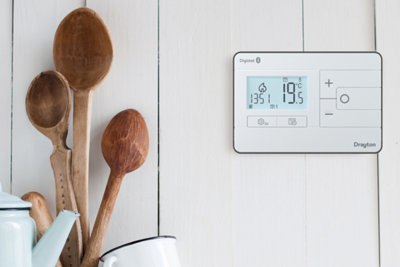 Digital thermostat installed on a kitchen wall.