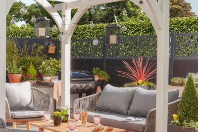 A modern white pergola providing a bright backdrop for lush greenery and colourful blooms.