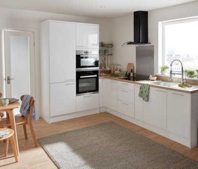 A white kitchen with gloss white cabinets, integrated appliances, light wood effect laminate flooring and a grey rug.