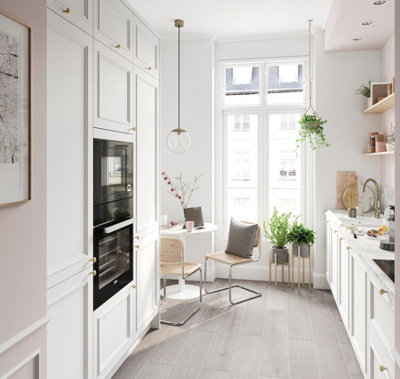 White kitchen with light grey flooring and a large window with lots of natural daylight.