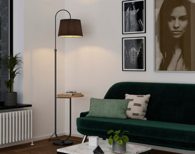 A white living room with a dark green sofa and a black floor lamp.