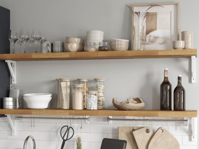 Wooden shelves in a kitchen with crockery, glasses, and storage containers.