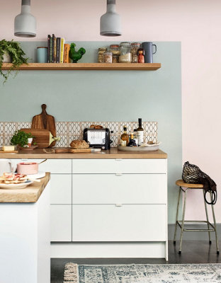 An open-plan kitchen with a light blue painted feature wall behind the cabinets, creating a distinct zone within the shared living space.